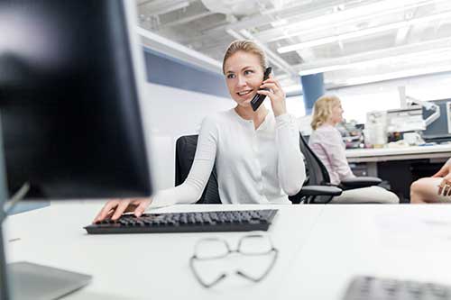 Frau arbeitet am PC mit Bluetooth-Tastatur