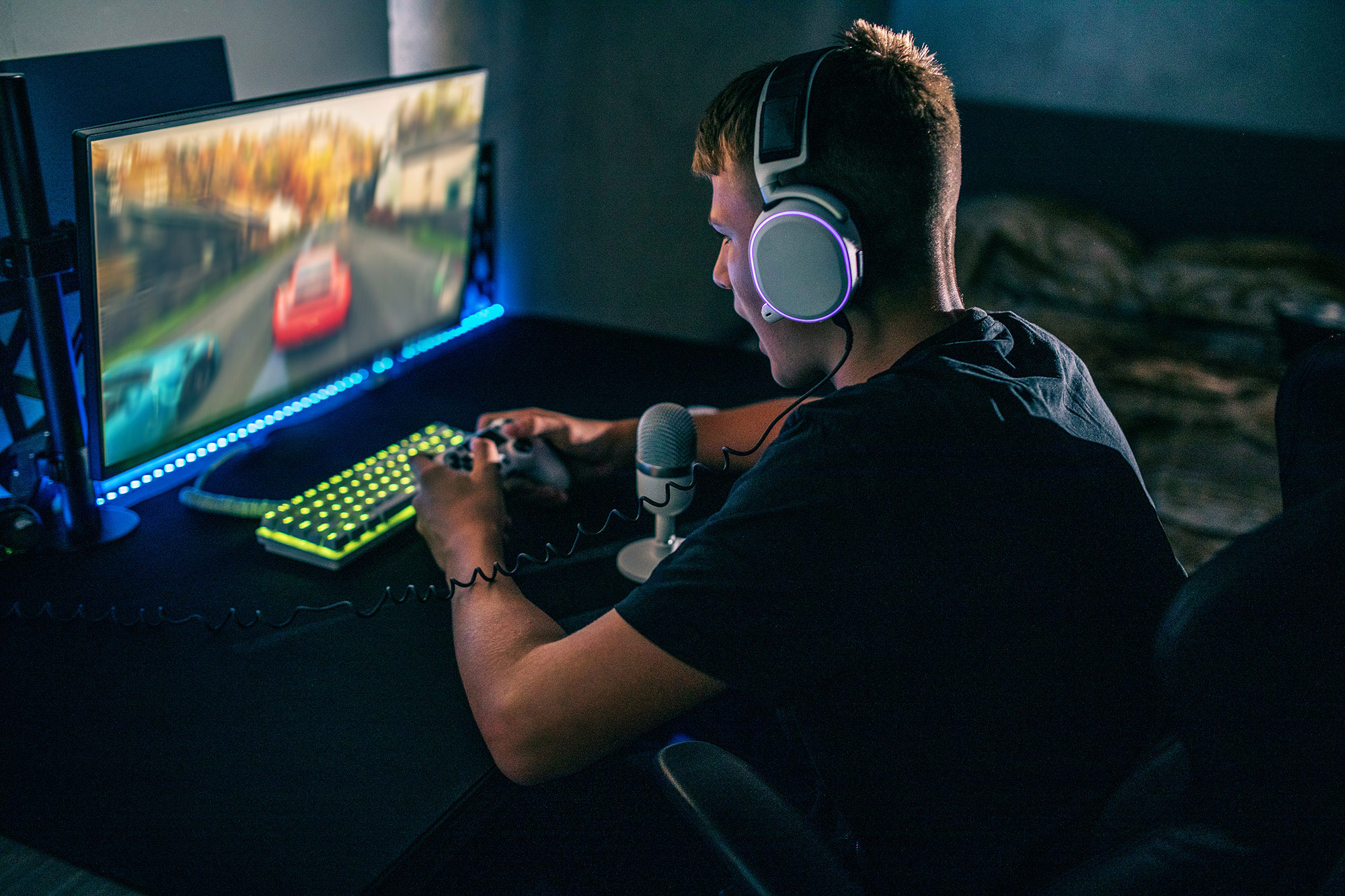 Junger Mann zockt am Computer und schaut auf Gaming-Monitor