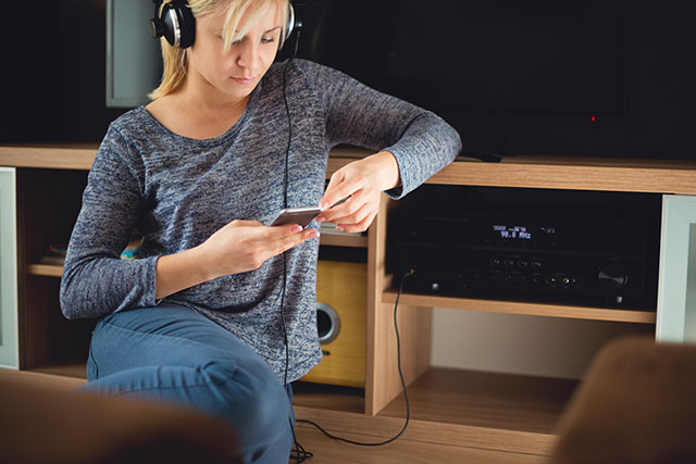 Hifi-Receiver für Musikfans: Frau mit Kopfhörern und Handy in der Hand