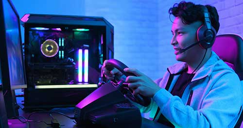 Junger Mann beim Gaming mit PC-Lenkrad